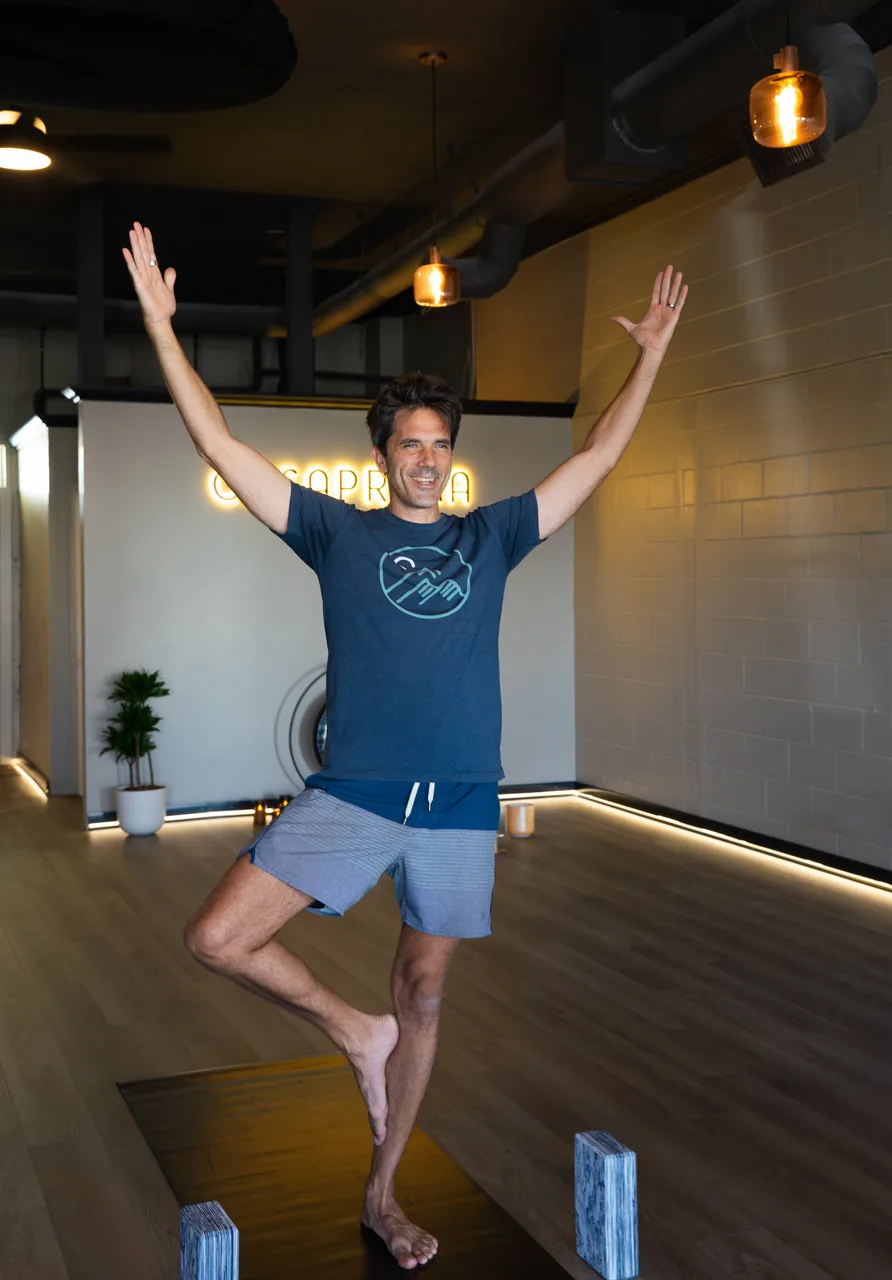 An instructor in tree pose with arms raised